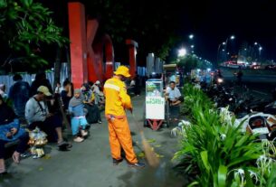 Seorang petugas kebersihan dari DLH Kota Bekasi terlihat bekerja di malam tahun baru 2025/2026