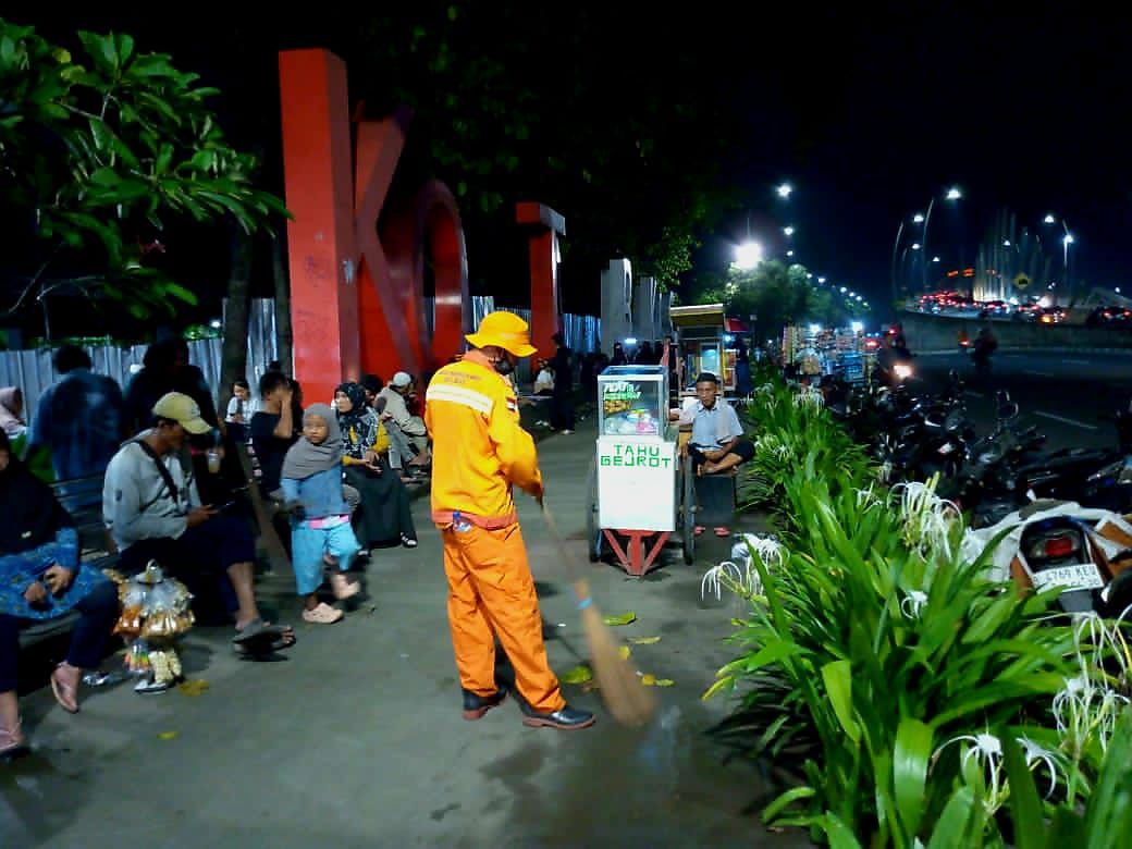 Seorang petugas kebersihan dari DLH Kota Bekasi terlihat bekerja di malam tahun baru 2025/2026